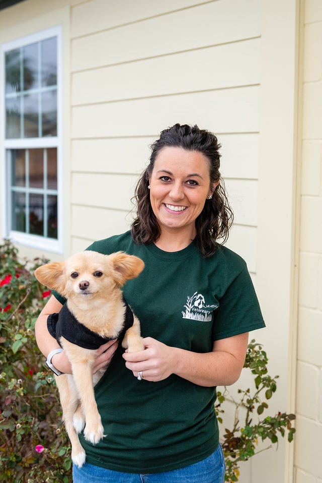 A woman holding a small dog in her arms.